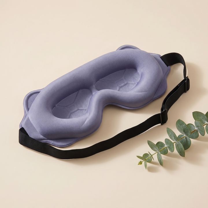 3D Contoured Sleep Mask in Dusty Lavender – styled with a eucalyptus sprig beside it, strap stretched out