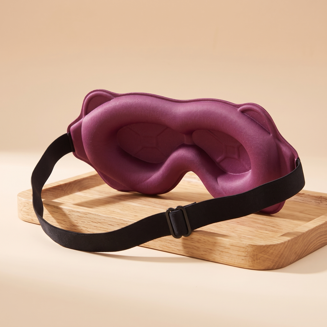 3D Contoured Sleep Mask in Plum – inside view resting on a wooden tray against a peach backdrop