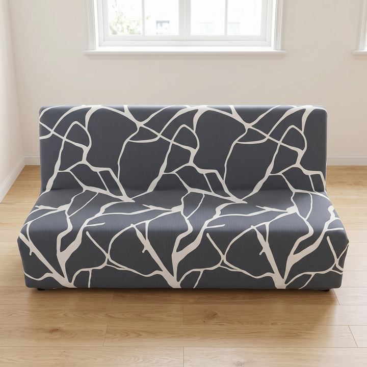 Stretch Futon Cover – Armless in Dark Gray – Branch Line – centered beneath a white-framed window in a bare room