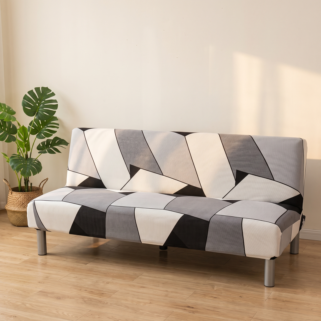 Stretch Futon Cover – Armless in Gray – Block Geometric – beside a leafy monstera plant with sunlight across the wall