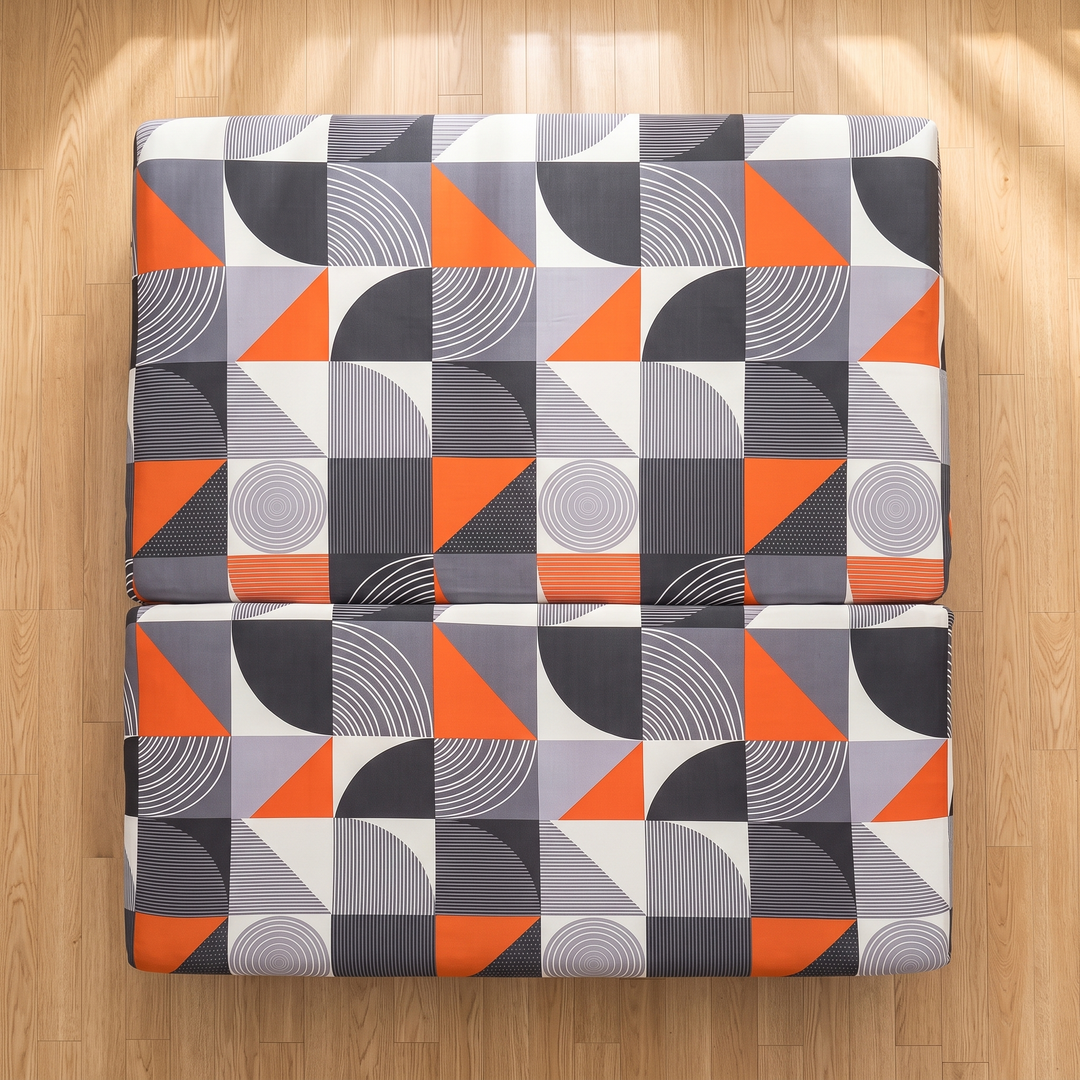 Stretch Futon Cover – Armless in Orange – Arc Geometric – top-down view of two covered sections laid on sunlit plank flooring