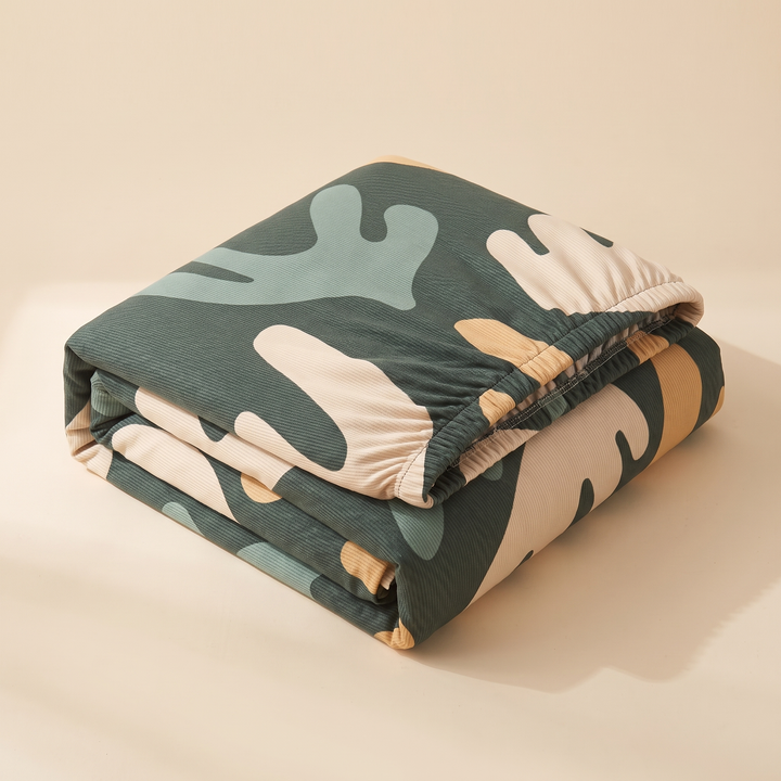 Stretch Futon Cover – Armless in Dark Green – Abstract Leaf – folded neatly with elastic hem visible on a plain beige background