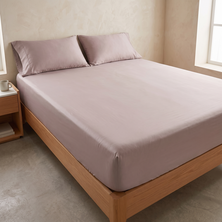 Bamboo Viscose Fitted Sheet Set with Pillowcases in Dusty Pink – three-quarter view of made bed between two sunlit windows