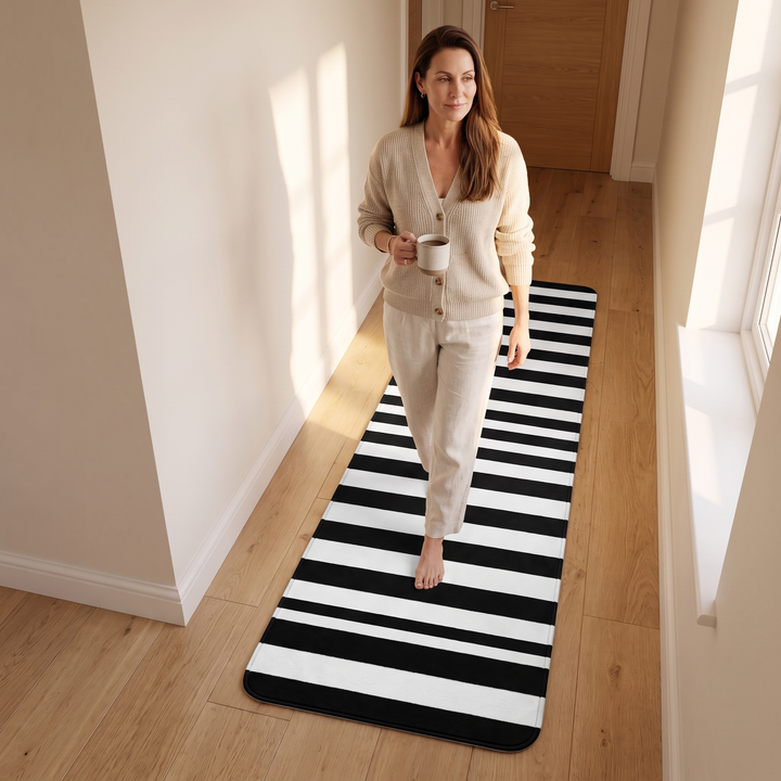 Black and White Runner Rug – Washable in Black &amp; White – Crosswise Stripe – barefoot woman walking along it holding a mug