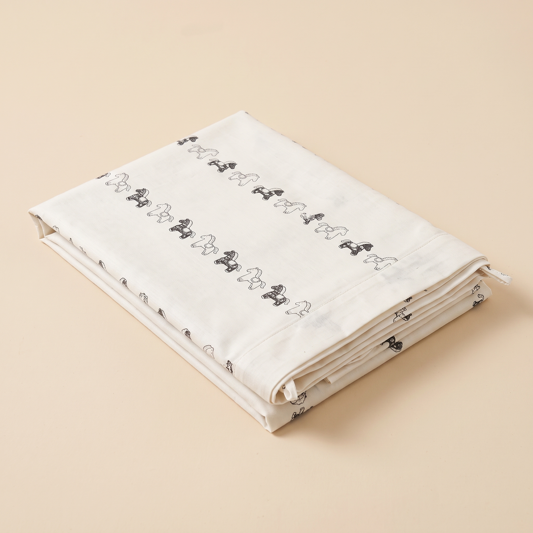 Body Pillowcase – Printed in White Rocking Horse – folded neatly on a plain peach background, seen from above at an angle