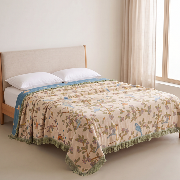 Boho Bird Bedspread – Reversible Gauze with Fringe in Oat – Leafy Birds – folded back to show blue reverse on bed