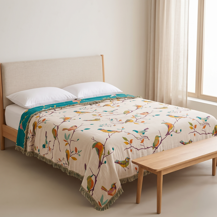 Boho Bird Bedspread – Reversible Gauze with Fringe in Cream – Songbirds – spread over a made bed with a wooden bench nearby