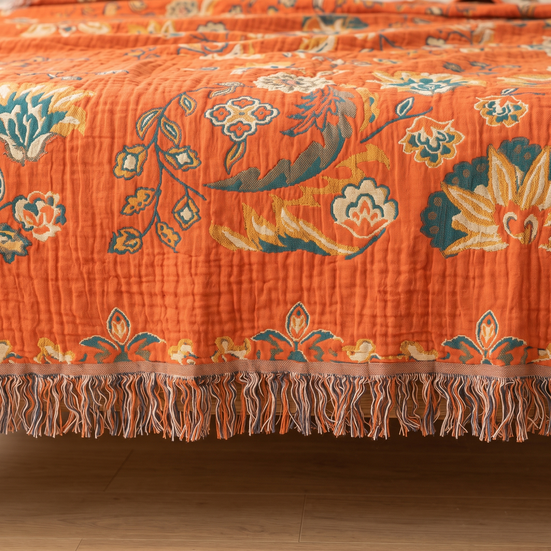 Boho Cotton Muslin Bedspread with Tassels in Orange – Floral – close-up of fringed edge hanging over a wood floor