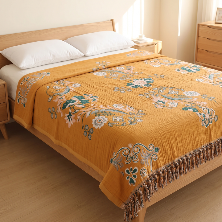 Boho Cotton Muslin Bedspread with Tassels in Mustard – Floral – three-quarter view of tasseled foot end beside a wooden dresser