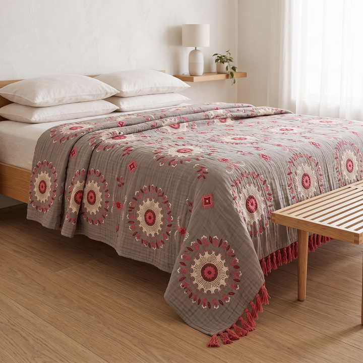 Boho Cotton Muslin Bedspread with Tassels in Rose – Medallion – draped over bed corner beside a slatted wooden bench