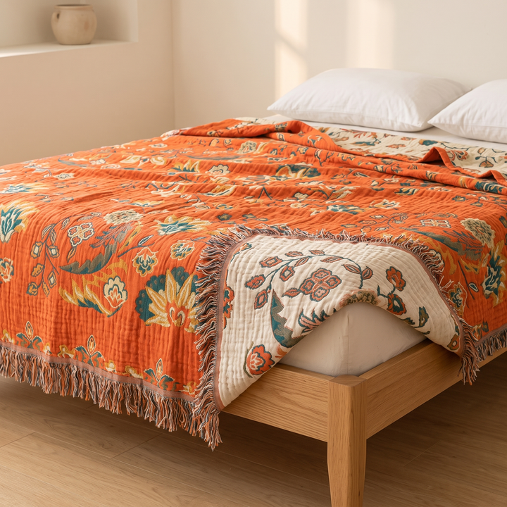 Boho Cotton Muslin Bedspread with Tassels in Orange – Floral – spread over a wooden bed with corner folded back