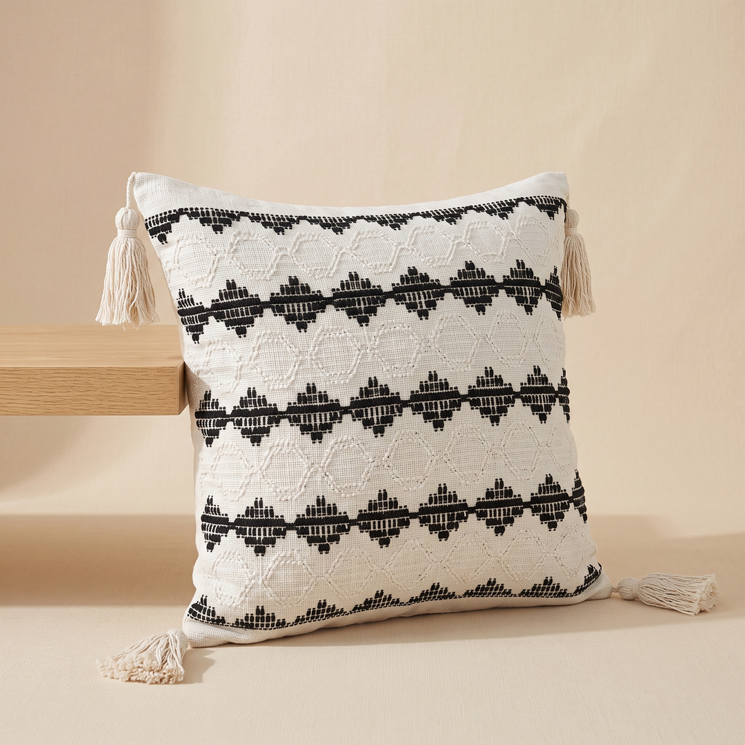 Boho Pillow Cover with Tassels – Woven in Cream – Black Dotted Diamond – tucked against a wooden ledge, side tassel trailing on floor