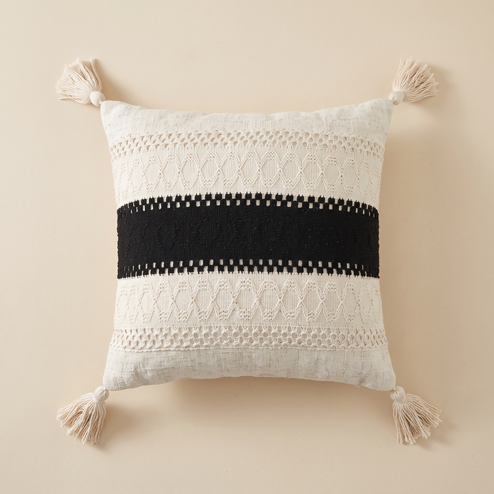 Boho Pillow Cover with Tassels – Woven in Cream – Black Stripe – lying flat and centered on a peach surface, shot straight down