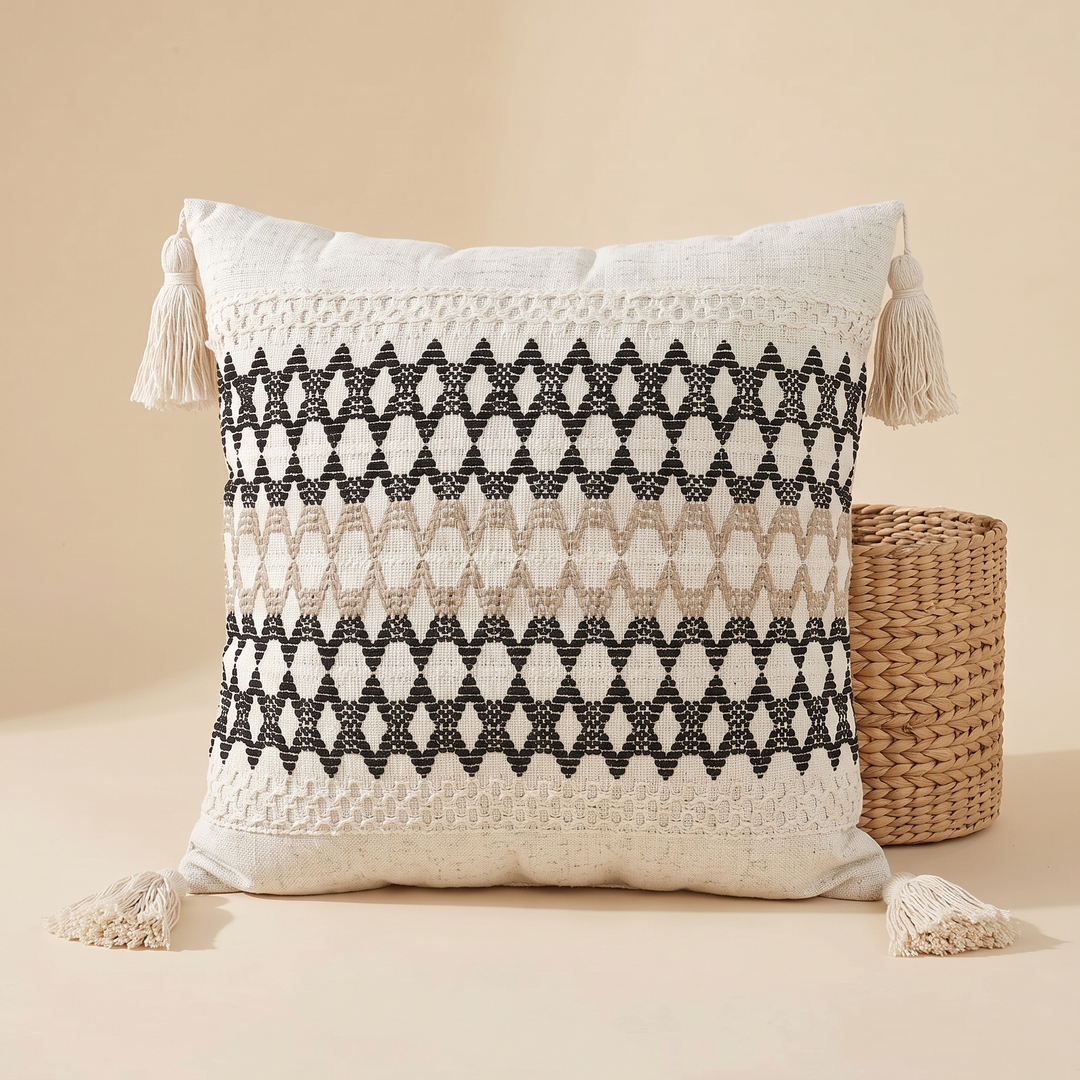 Boho Pillow Cover with Tassels – Woven in Cream – Tan &amp; Black Diamond – propped against a round woven wicker basket