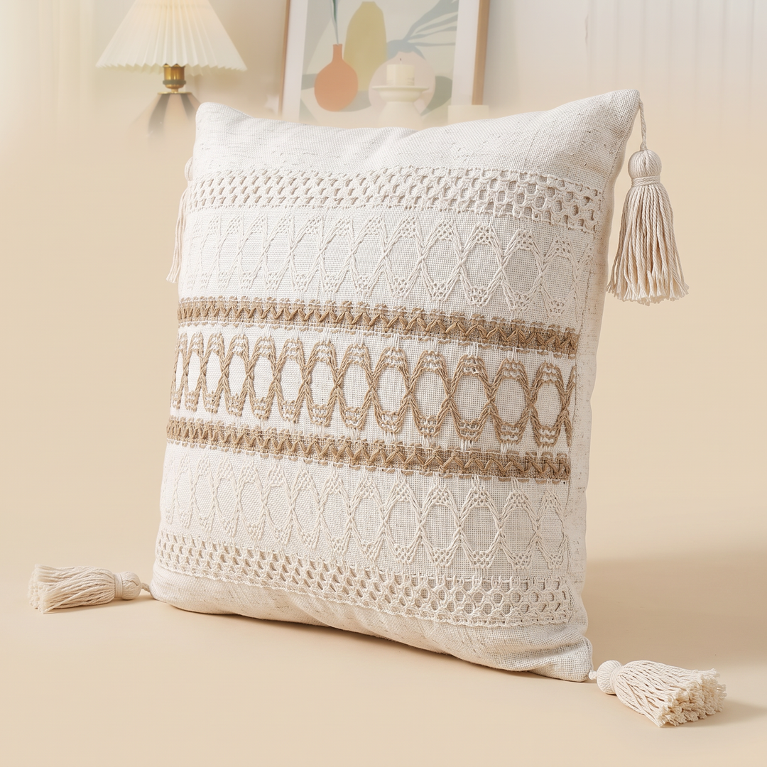 Boho Pillow Cover with Tassels – Woven in Cream – Tan Ladder – in front of a pleated wall lamp and framed print