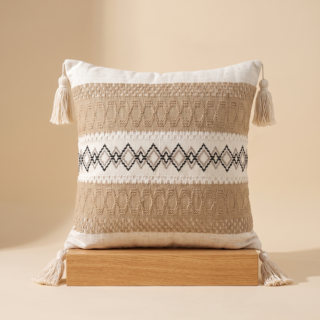 Boho Pillow Cover with Tassels – Woven in Tan – Black Zigzag – centered on a chunky oak block in warm studio light