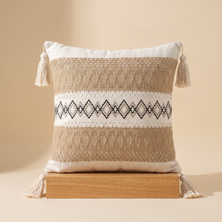 Boho Pillow Cover with Tassels – Woven in Tan – Black Zigzag – centered on a chunky oak block in warm studio light