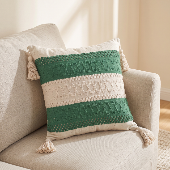 Boho Pillow Cover with Tassels – Woven in Cream – Green Stripe – angled on a beige linen armchair in a sunlit room