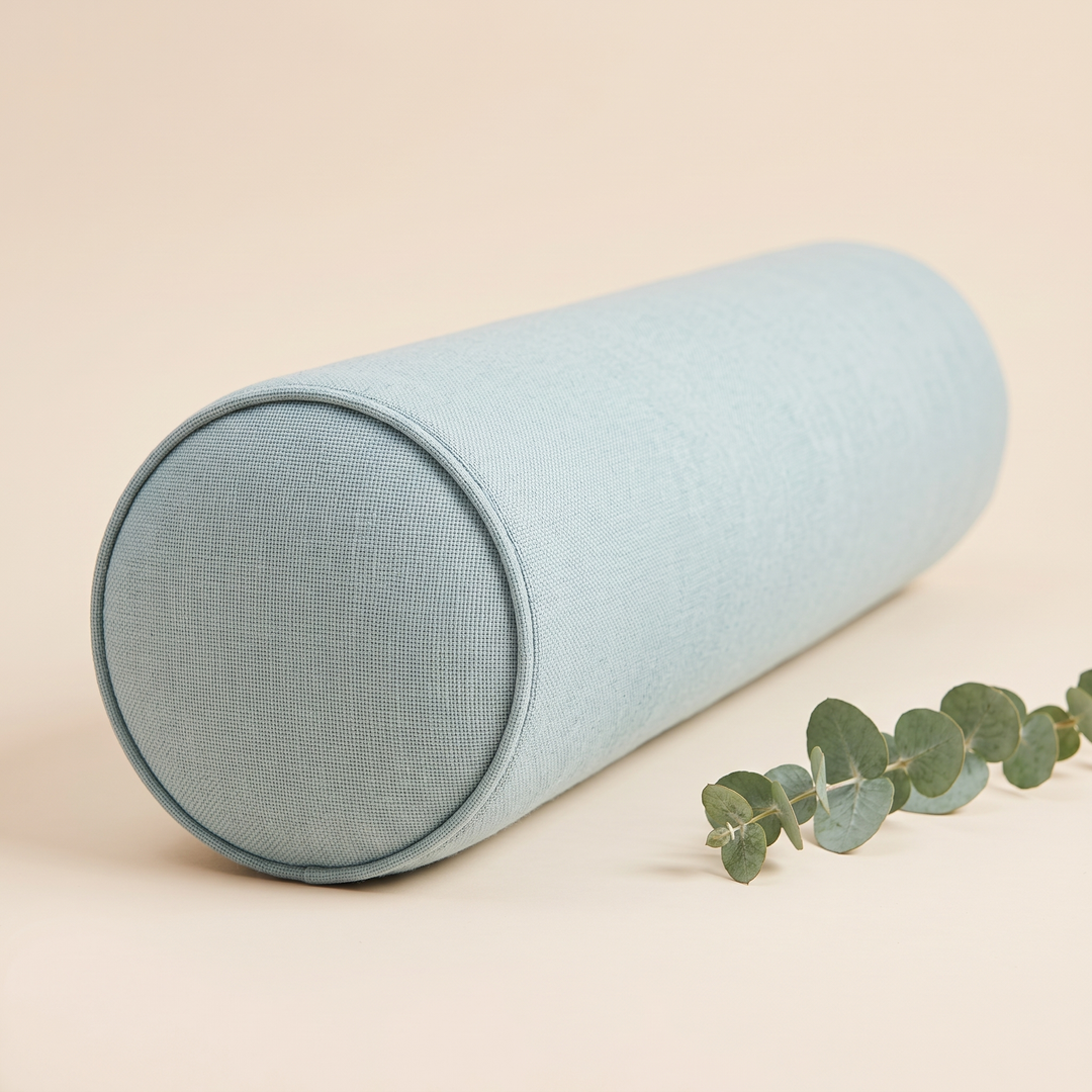 Bolster Pillow in Aqua – with a eucalyptus sprig lying beside it, three-quarter angle