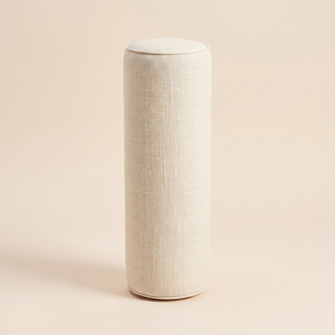 Bolster Pillow in Cream – standing upright on a peach background with soft shadow
