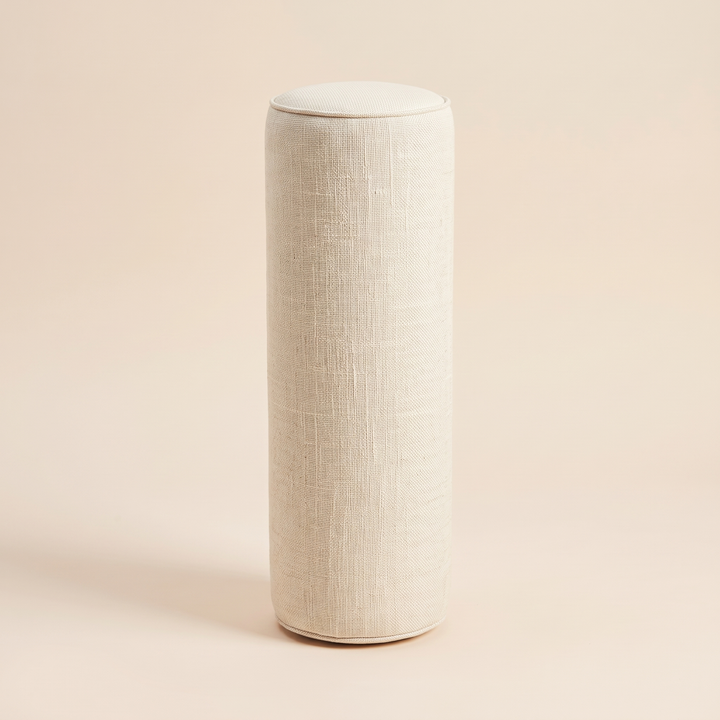 Bolster Pillow in Cream – standing upright on a peach background with soft shadow