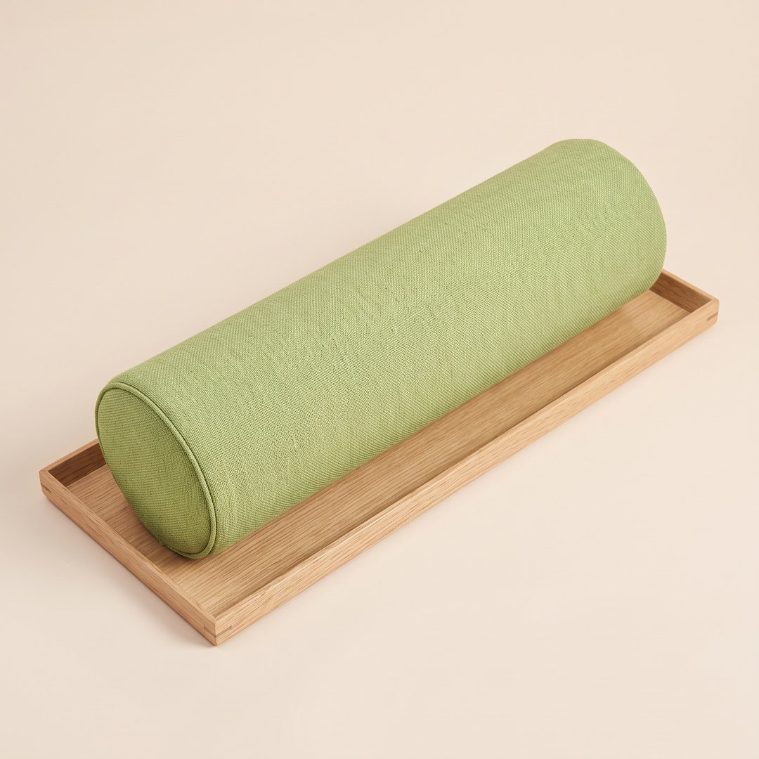 Bolster Pillow in Moss Green – lying on a shallow oak tray, angled overhead view