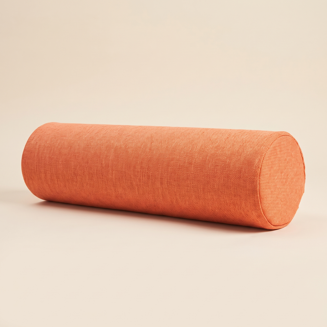 Bolster Pillow in Orange – lying on its side against a plain cream background