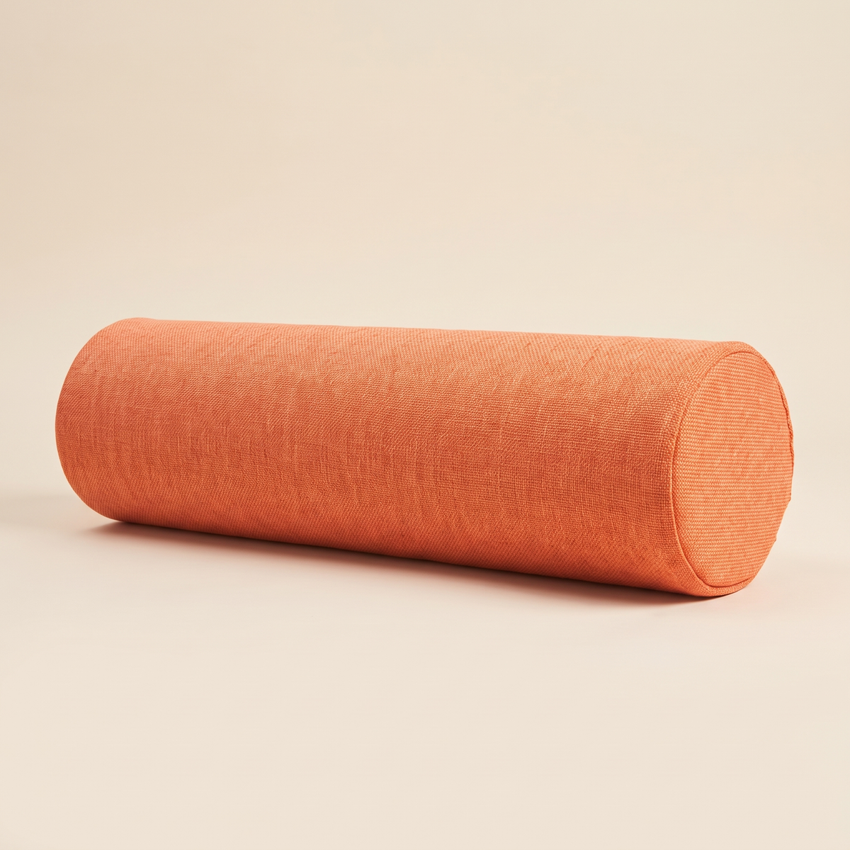 Bolster Pillow in Orange – lying on its side against a plain cream background