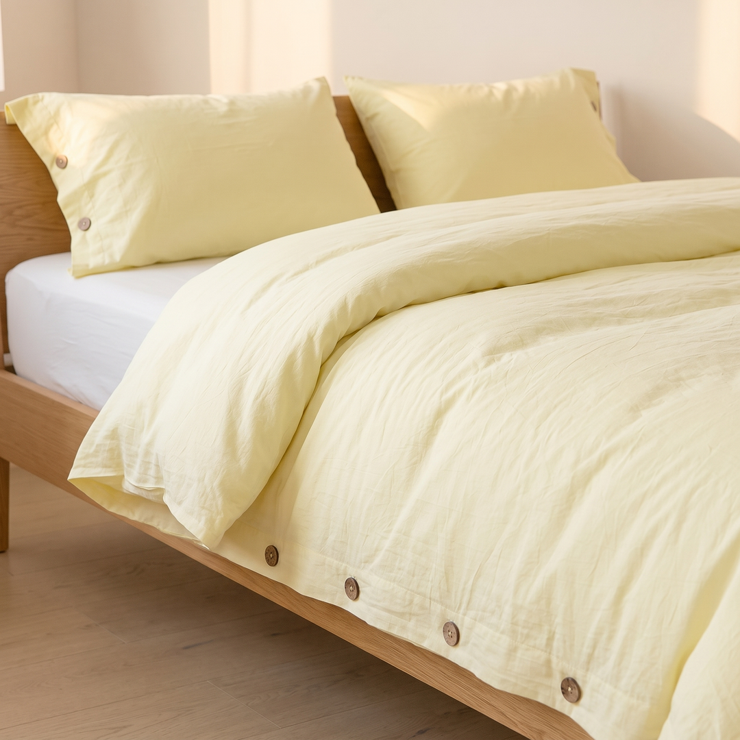 Cotton Duvet Cover Set with Buttons in Light Yellow – bed with soft light and shadows on the wall behind