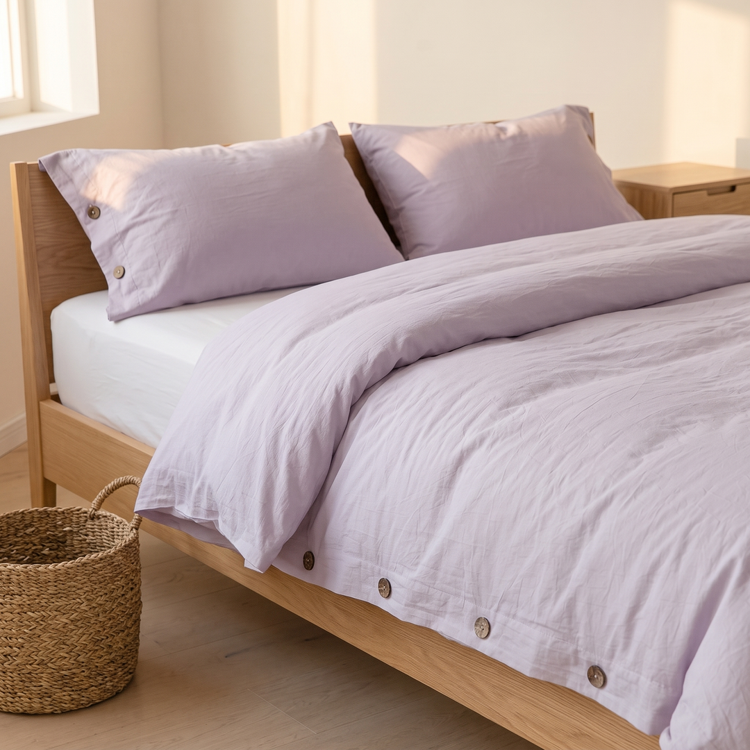 Cotton Duvet Cover Set with Buttons in Lilac – beside a woven seagrass basket on a light wood floor