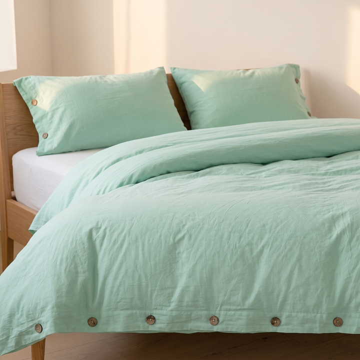 Cotton Duvet Cover Set with Buttons in Mint Green – side angle of crinkled duvet draping over bed edge
