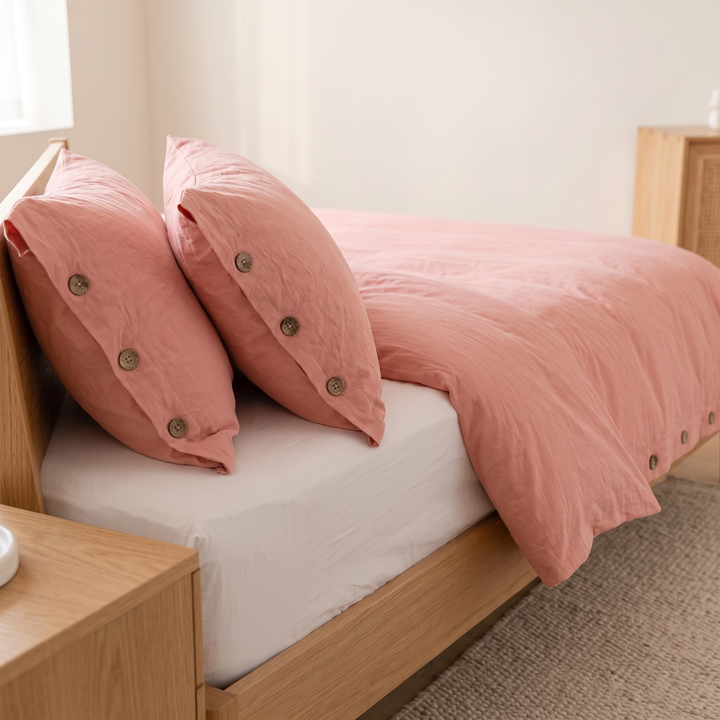 Cotton Duvet Cover Set with Buttons in Pink – pillows against headboard with white fitted sheet exposed