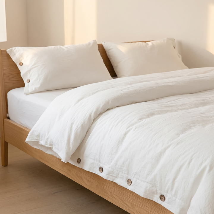 Cotton Duvet Cover Set with Buttons in White – on a made bed with an oak frame in a sunlit bedroom