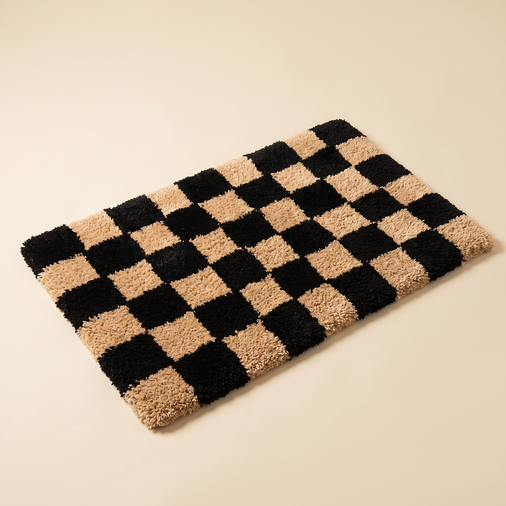 Checkered Bath Rug – Plush, Non-Slip in Black and Tan – laid flat at an angle on a plain cream background