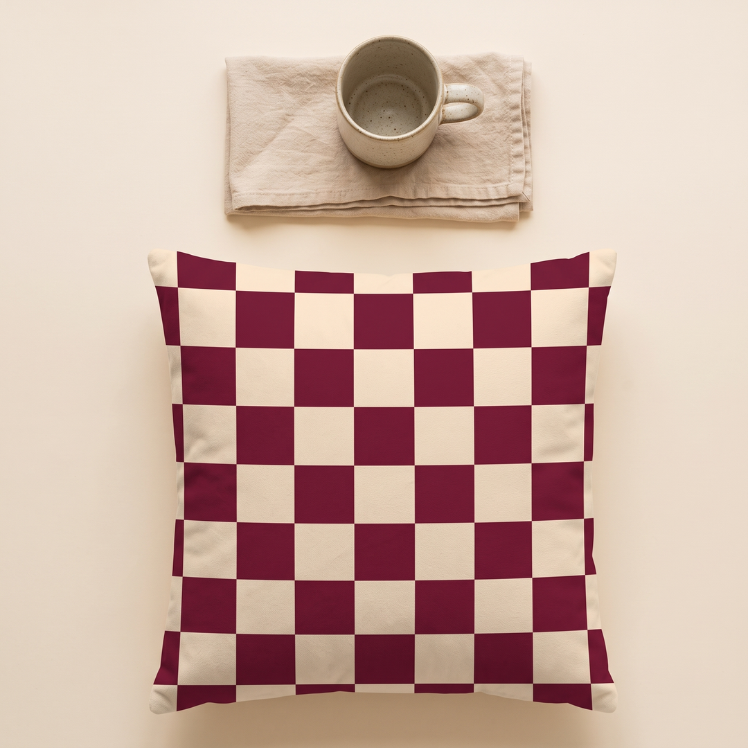 Checkered Pillow Cover in Burgundy &amp; Sand Check – top-down view below a speckled mug on a folded napkin
