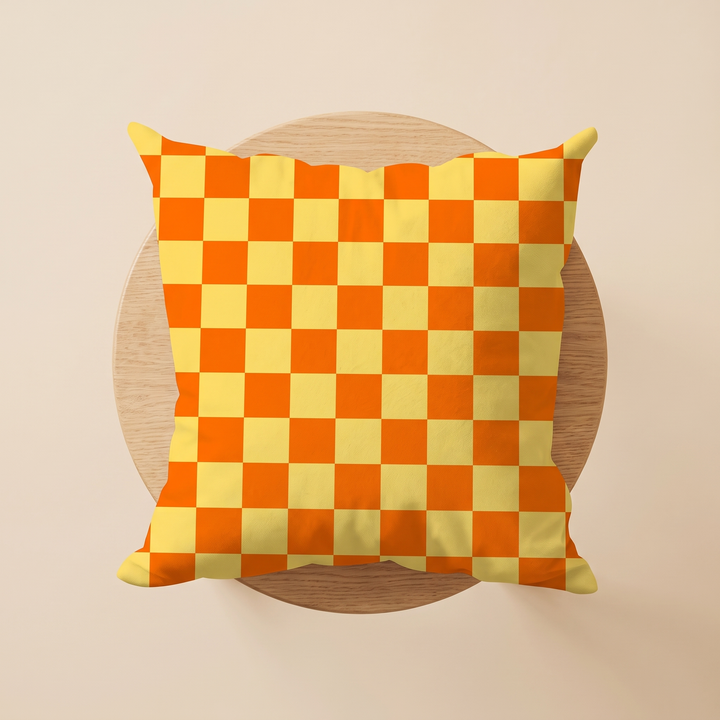 Checkered Pillow Cover in Orange &amp; Yellow Check – on a round wooden stool, straight overhead view