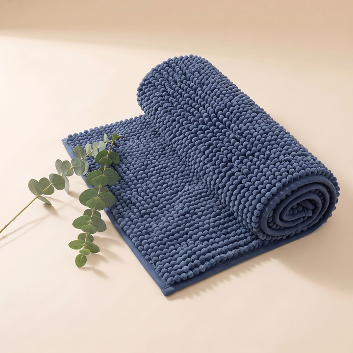 Chenille Bath Mat – Non-Slip in Navy Blue – rolled up loosely with eucalyptus sprigs beside it