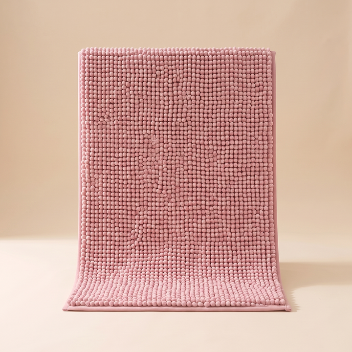 Chenille Bath Mat – Non-Slip in Pink – standing upright against a beige studio backdrop, front view with bottom end curled forward