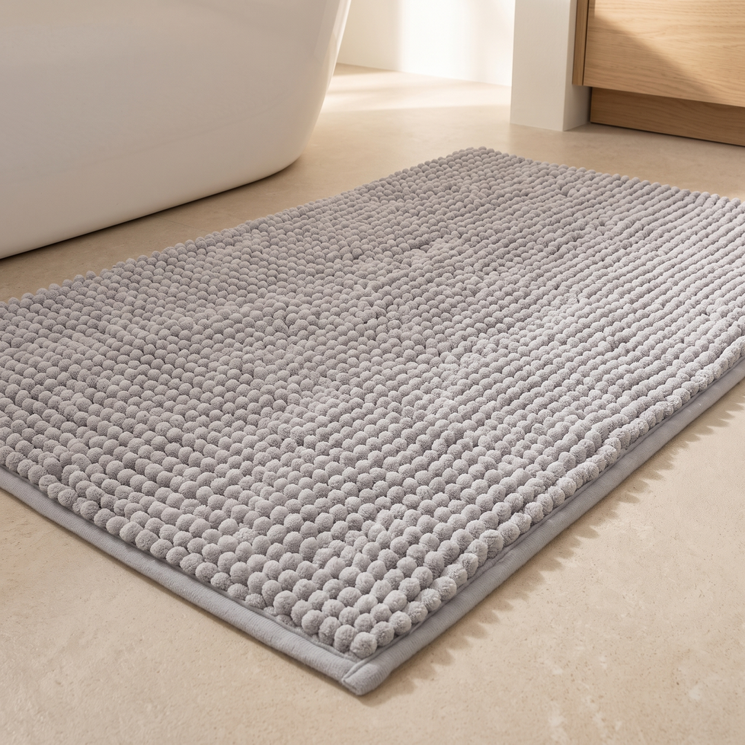 Chenille Bath Mat – Non-Slip in Gray – on a beige tile floor beside a freestanding bathtub