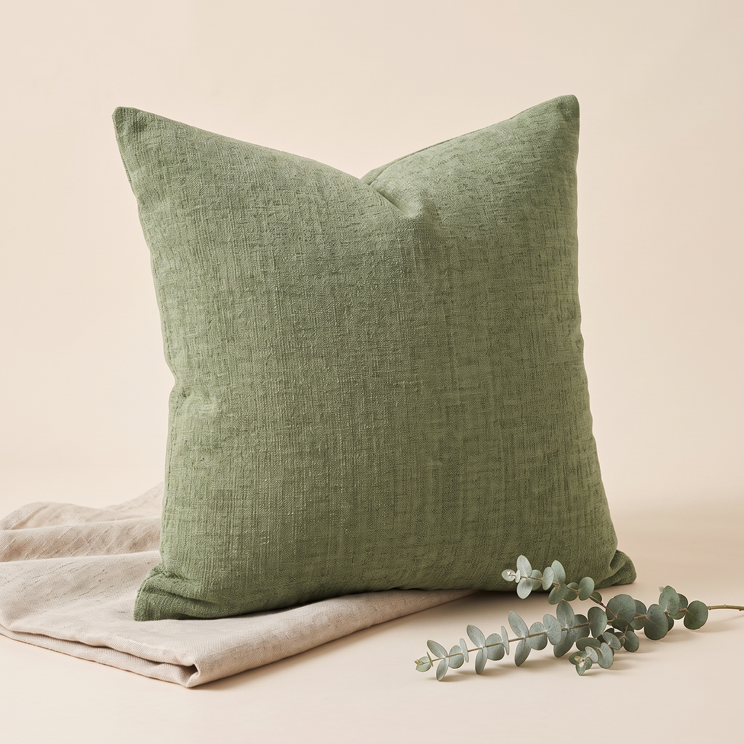 Chenille Throw Pillow Cover in Olive Green – styled with a eucalyptus sprig lying in the foreground