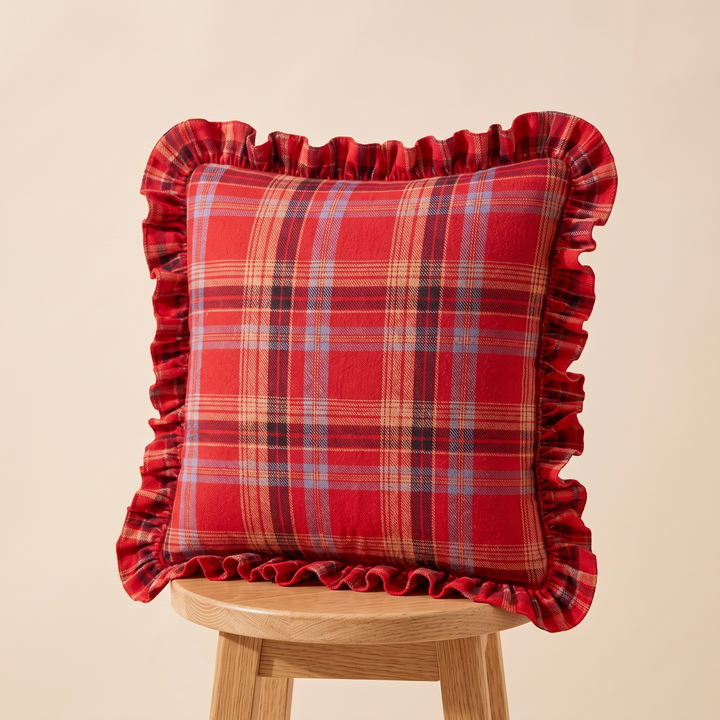 Christmas Plaid Pillow Cover in Red – Tartan – propped on a wooden stool against a plain backdrop