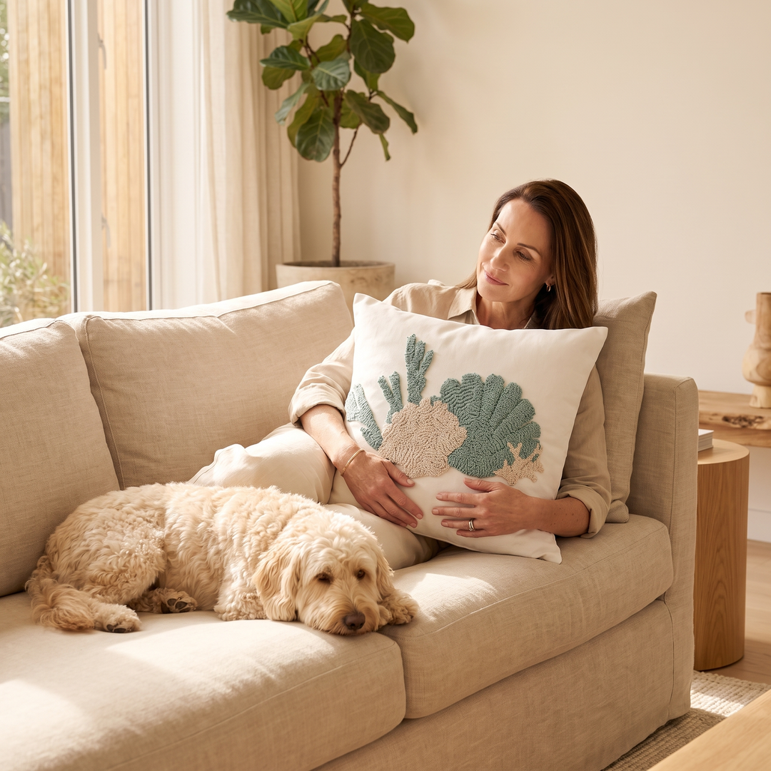 Coastal Throw Pillow Cover – Tufted in Sea Green – Shell – held by a seated woman on a sofa beside a sleeping dog