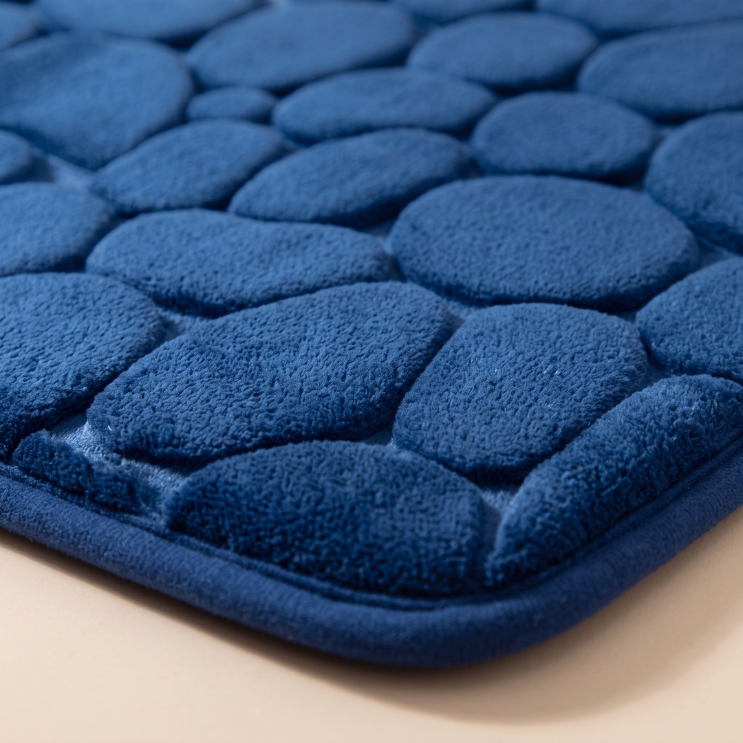 Non-Slip Memory Foam Bath Mat – Cobblestone in Royal Blue – close-up of the corner and raised pebble pattern on a beige surface