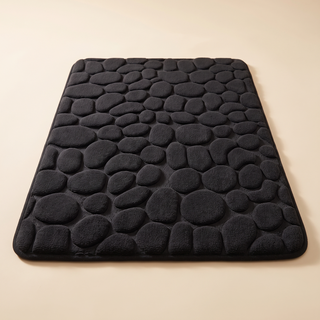 Non-Slip Memory Foam Bath Mat – Cobblestone in Black – low-angle view along its length with raised pebbles receding into the distance