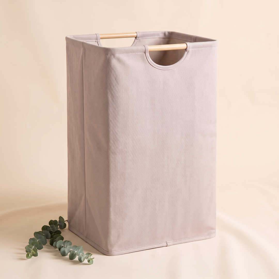 Collapsible Laundry Basket in Light Taupe – three-quarter angle with a eucalyptus sprig on draped fabric