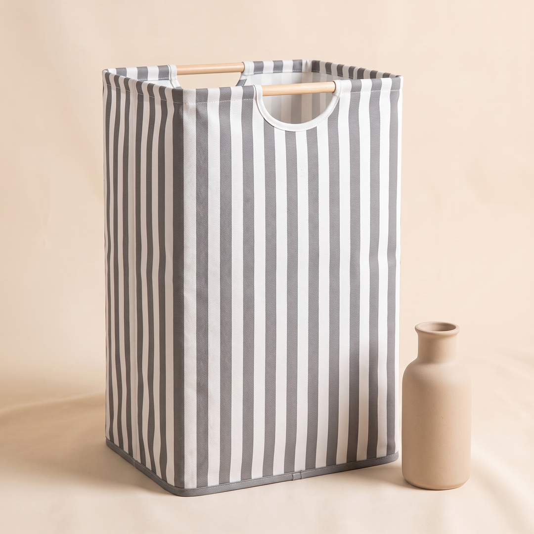 Collapsible Laundry Basket in White &amp; Gray Stripe – standing next to a small ceramic bottle vase