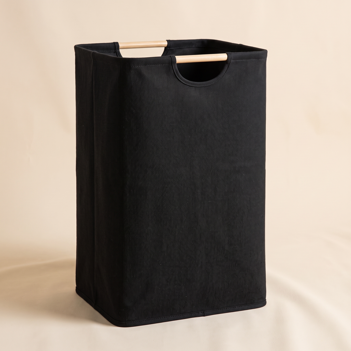 Collapsible Laundry Basket in Black – standing upright with wooden handles against a plain cream backdrop