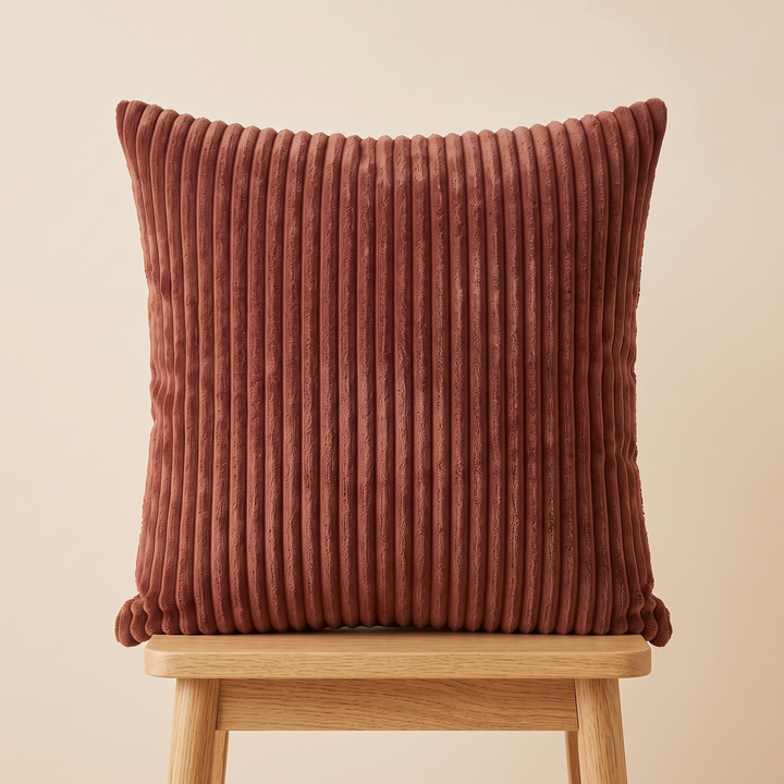 Corduroy Pillow Cover in Chocolate Brown – upright on a light wooden stool against a beige wall