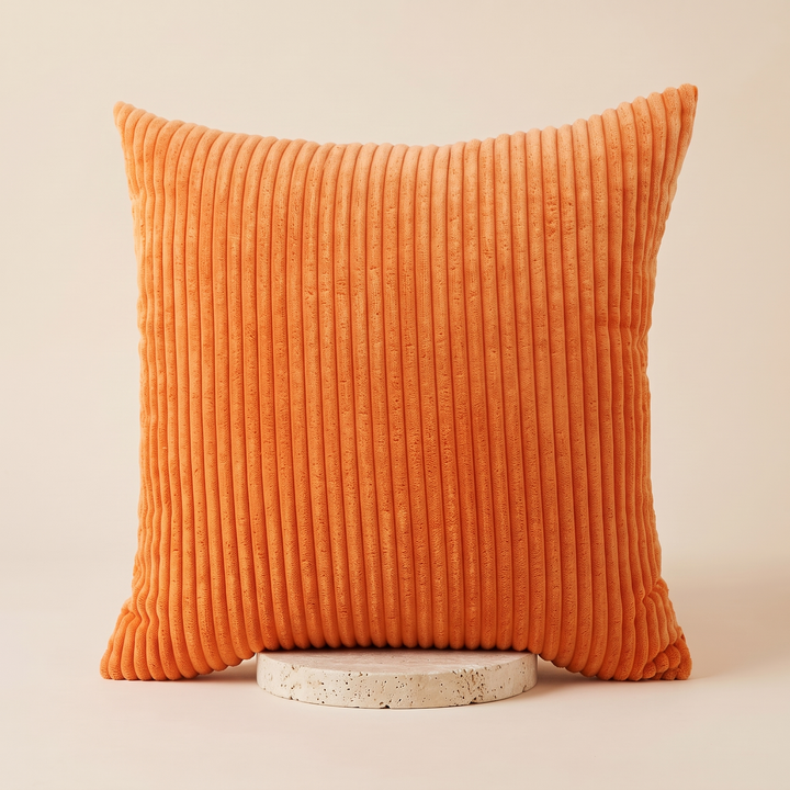 Corduroy Pillow Cover in Orange – propped on a round speckled stone disc against a plain backdrop