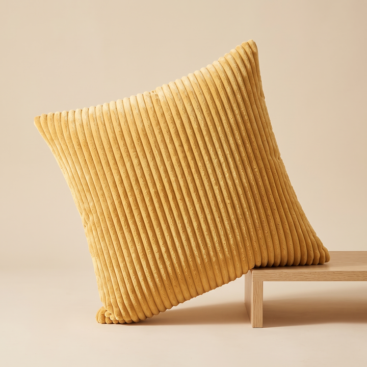 Corduroy Pillow Cover in Yellow – tilted with one side resting on a low wooden platform